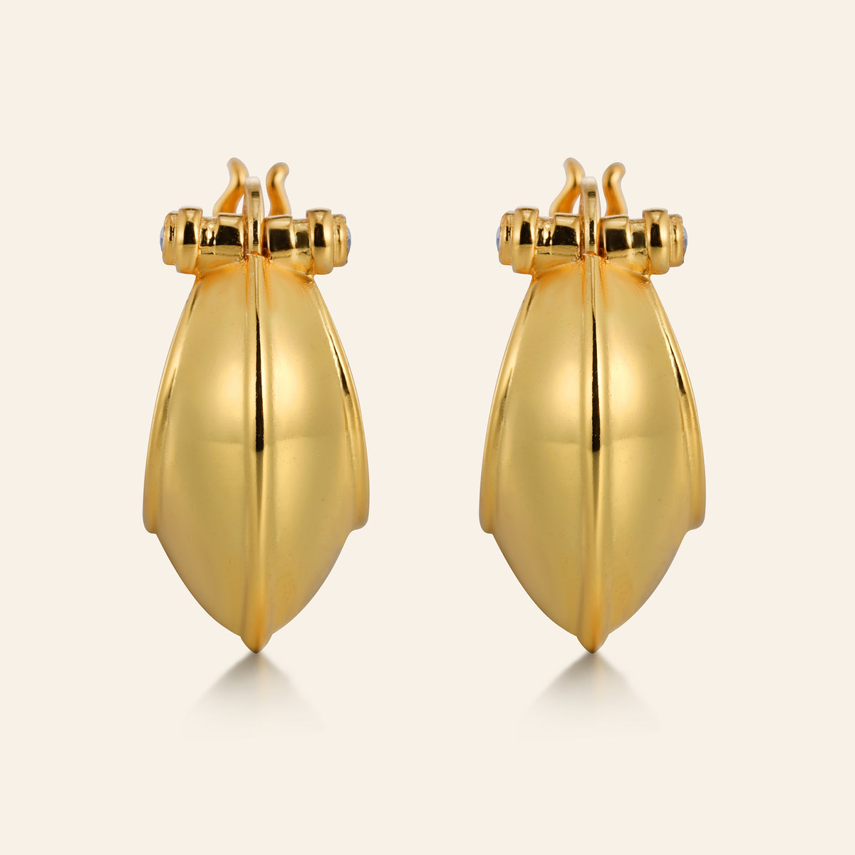 Pair of gold earrings on a light beige background
