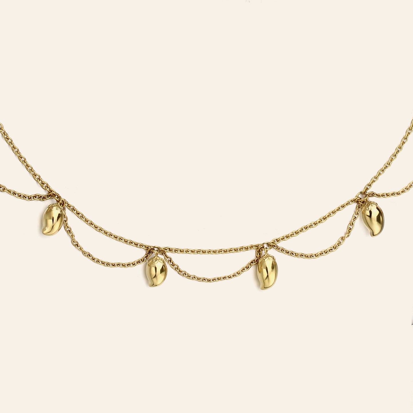 A gold chain necklace featuring five dangling mango charms, displayed against a solid off-white background.