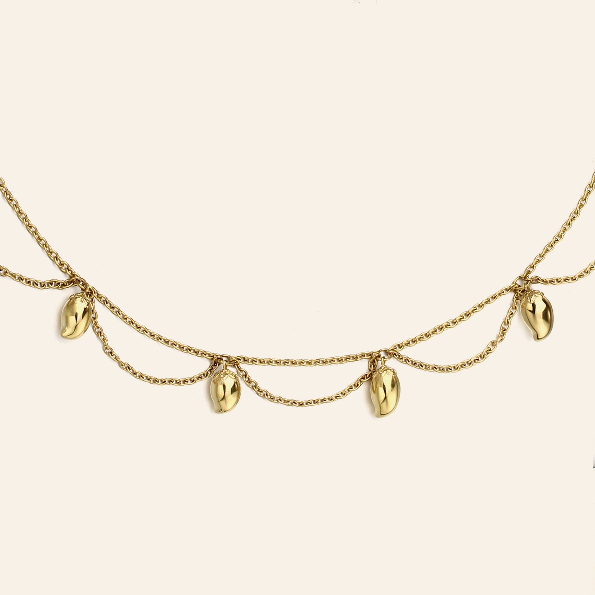 A gold chain necklace featuring five dangling mango charms, displayed against a solid off-white background.