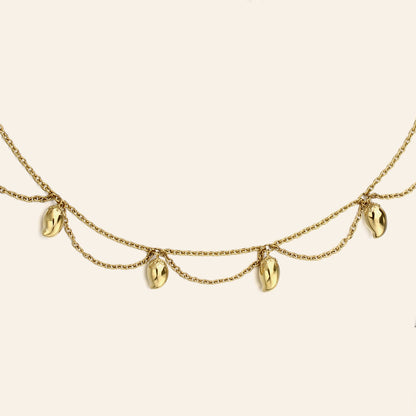 A gold chain necklace featuring five dangling mango charms, displayed against a solid off-white background.