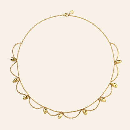 A delicate gold necklace with a fine chain and multiple small mango charms, displayed on a light cream background.