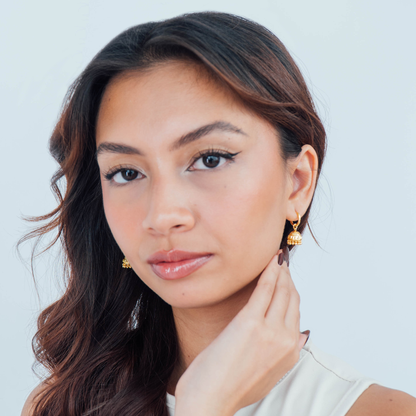 Woman wearing gold earrings against a light background