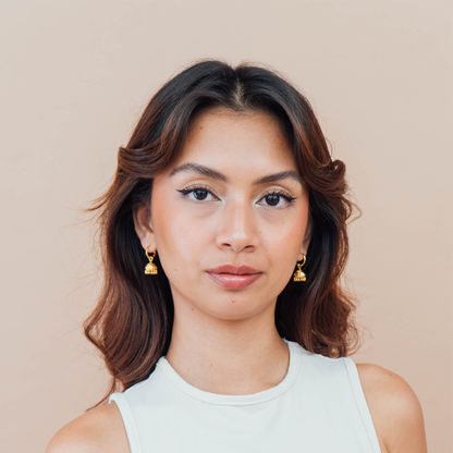 Woman wearing gold earrings against a beige background
