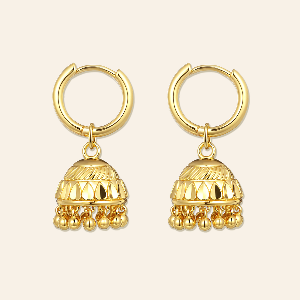 Pair of gold hoop earrings with dangling gold balls on a beige background