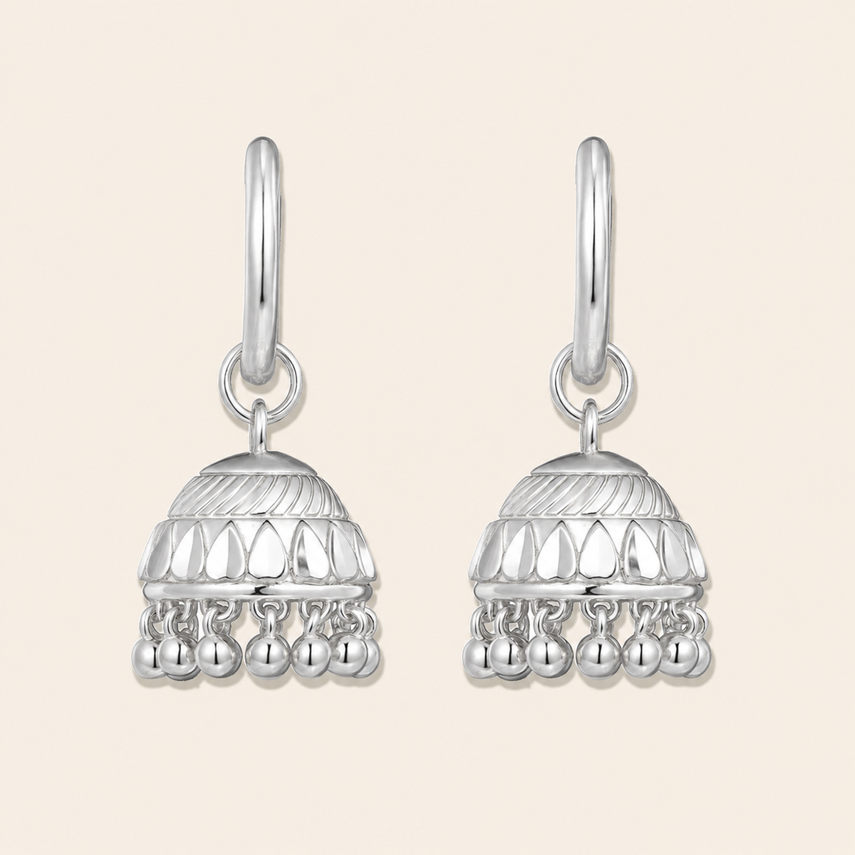 Pair of silver earrings with intricate designs on a beige background