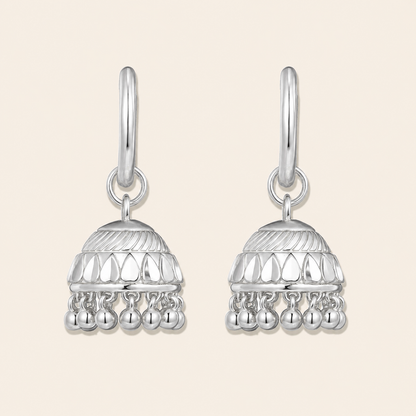 Pair of silver earrings with intricate designs on a beige background