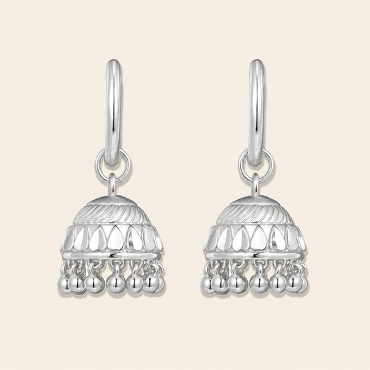 Pair of silver earrings with intricate designs on a beige background