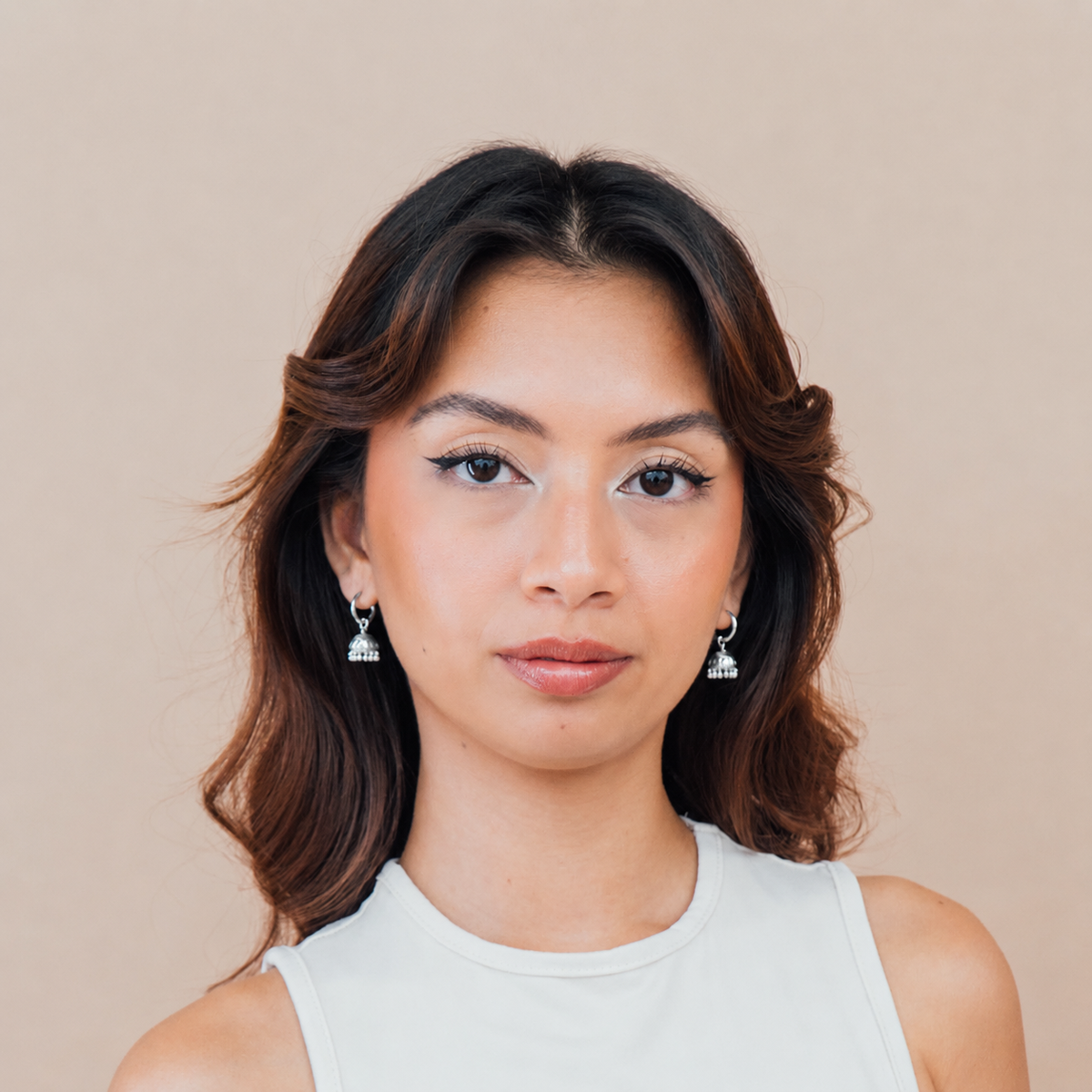 Woman wearing earrings against a beige background
