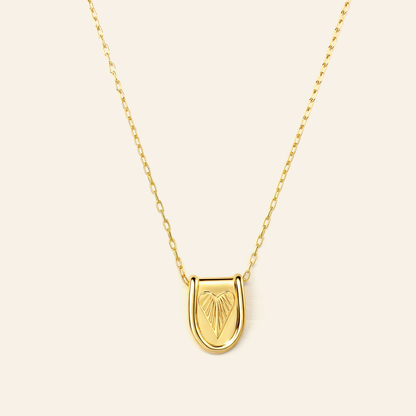 Gold necklace with a heart-shaped pendant on a beige background