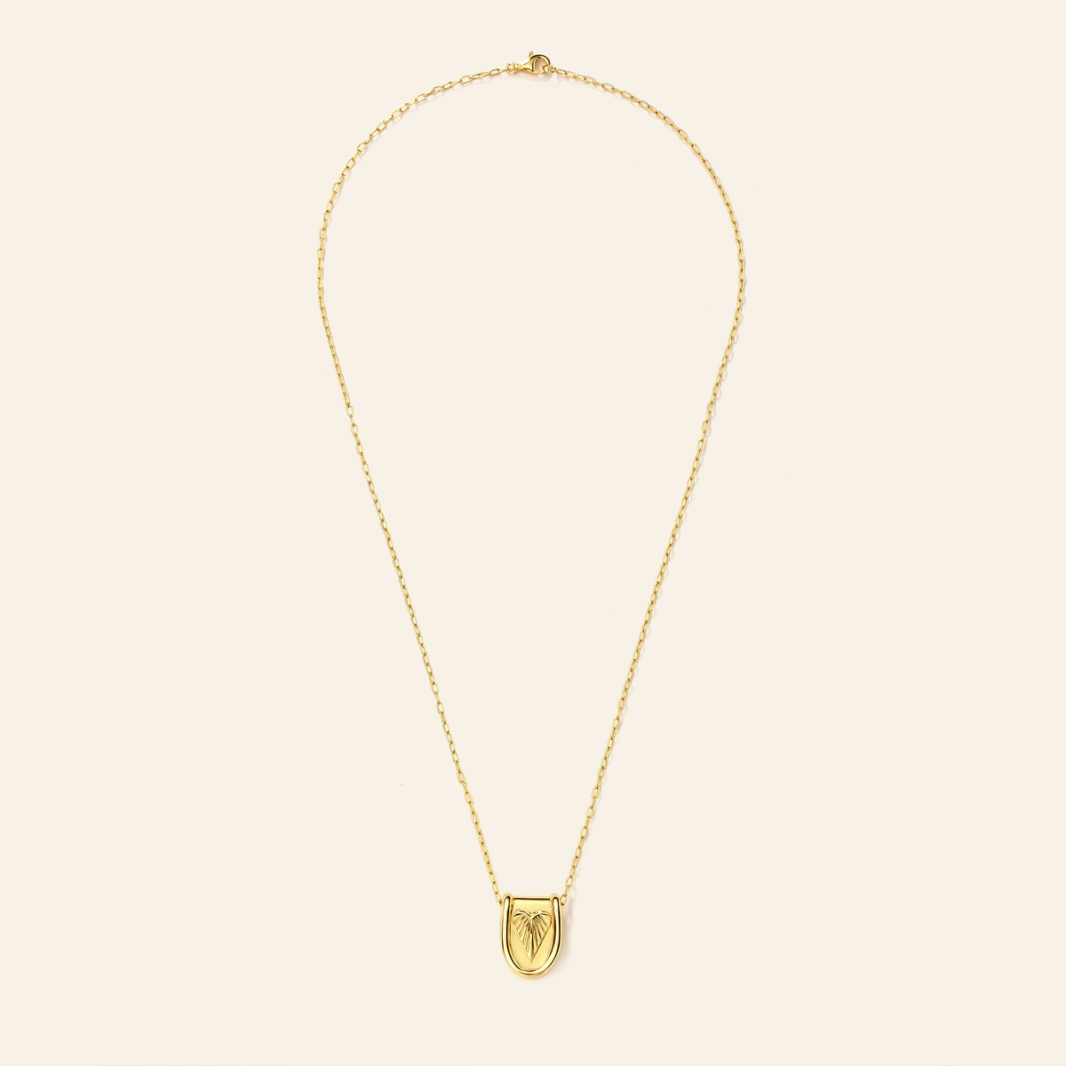 Gold necklace with a shield pendant on a beige background
