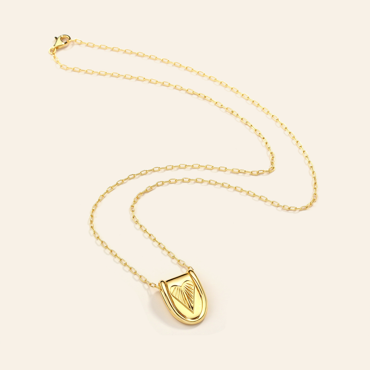 Gold necklace with a pendant on a light beige background