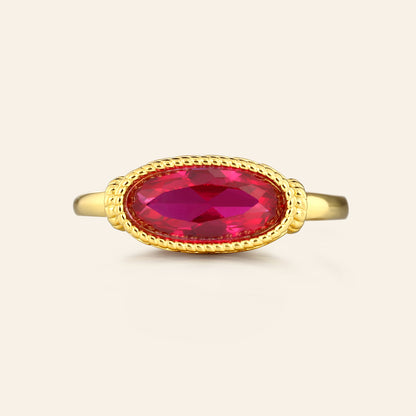 Gold ring with a red gemstone on a beige background
