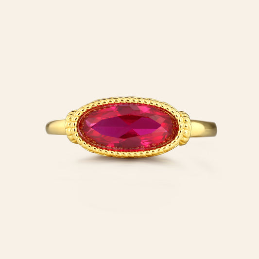 Gold ring with a red gemstone on a beige background
