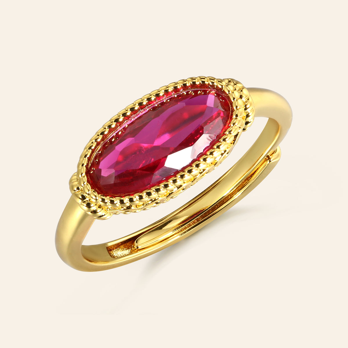 Gold ring with a red gemstone on a light beige background