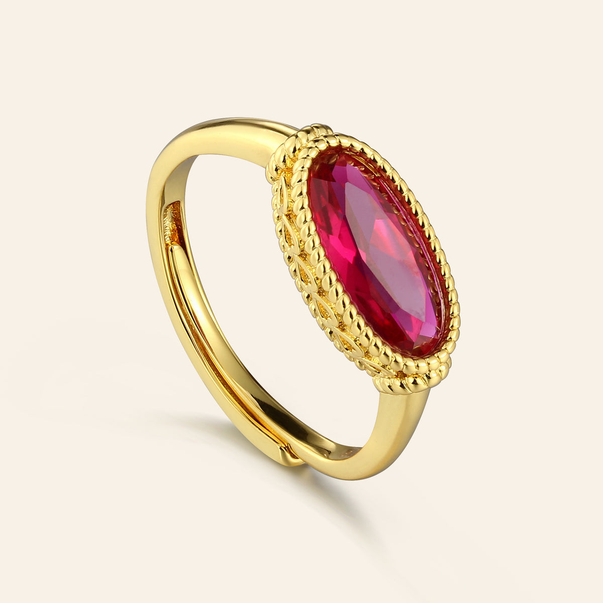 Gold ring with a red gemstone on a light beige background