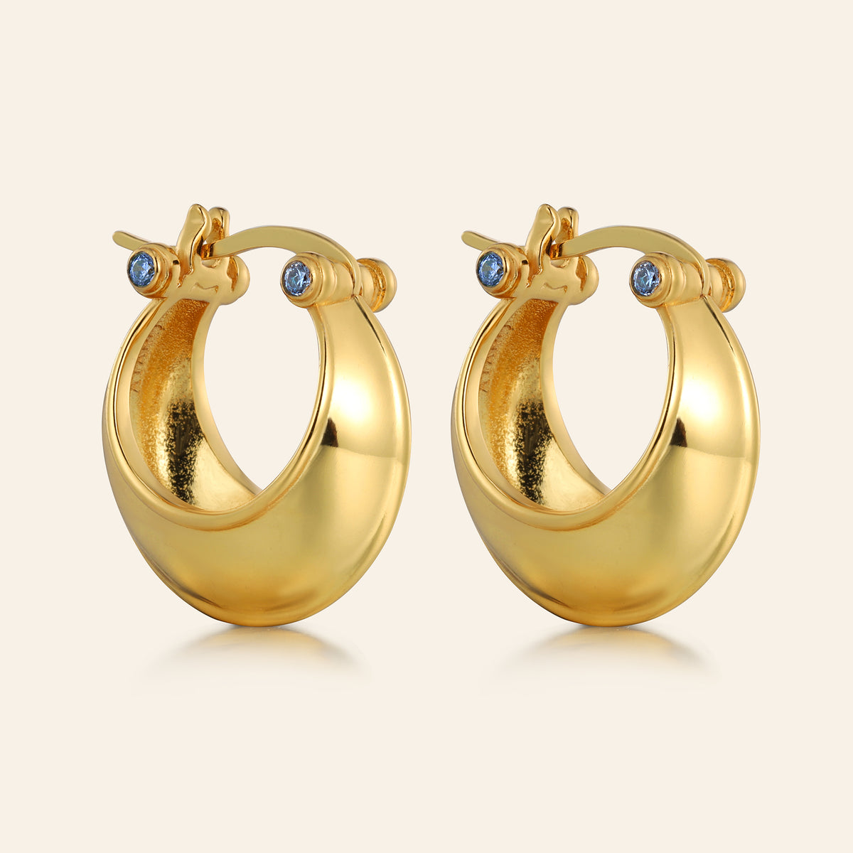 Pair of gold hoop earrings with small blue stones on a white background