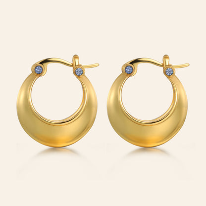 Gold hoop earrings with small blue stones on a beige background