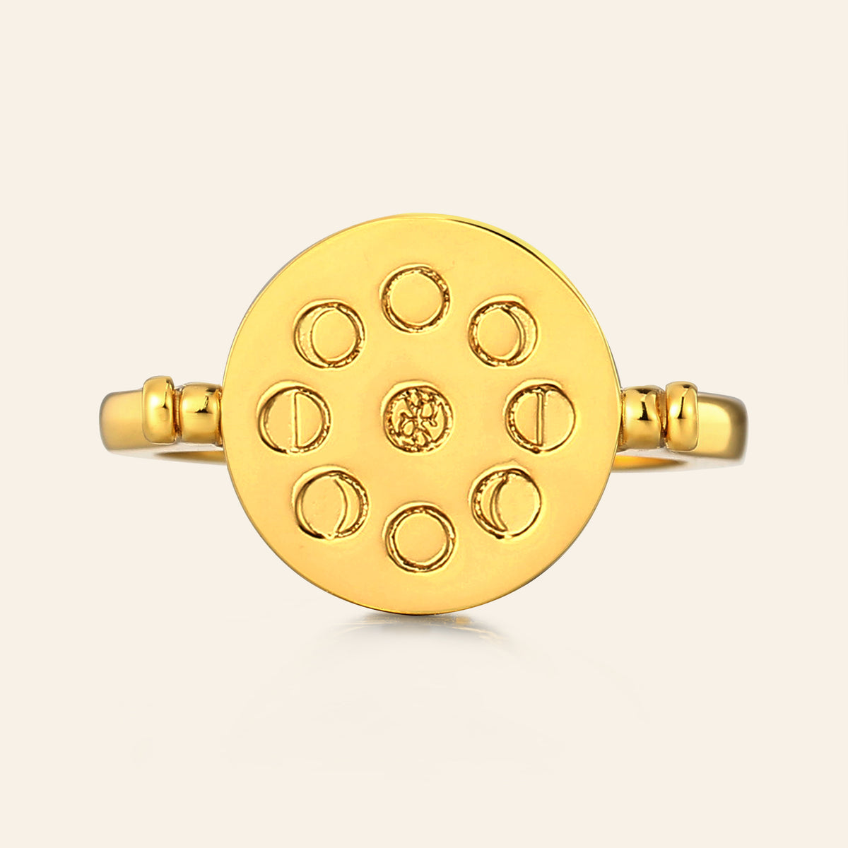Gold ring with moon phase design on a light beige background