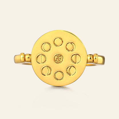 Gold ring with moon phase design on a light beige background