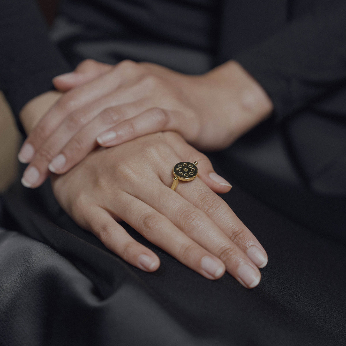 Close-up of hands with a gold ring on a dark background