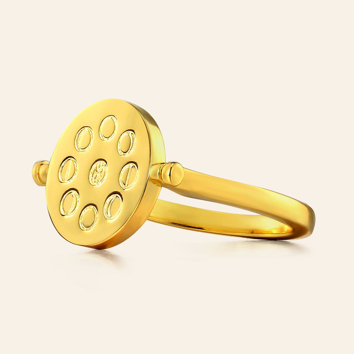 Gold ring with circular design on a beige background