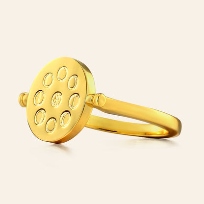 Gold ring with circular design on a beige background