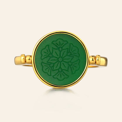 Gold ring with a green circular design on a beige background