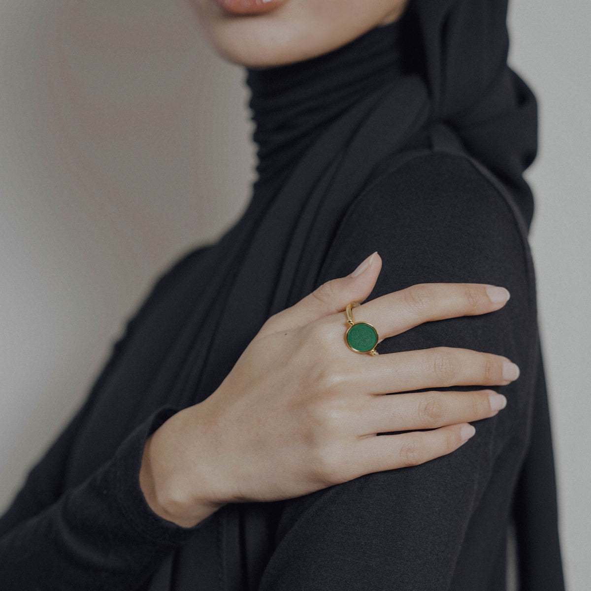 Person wearing a green ring on a blurred background