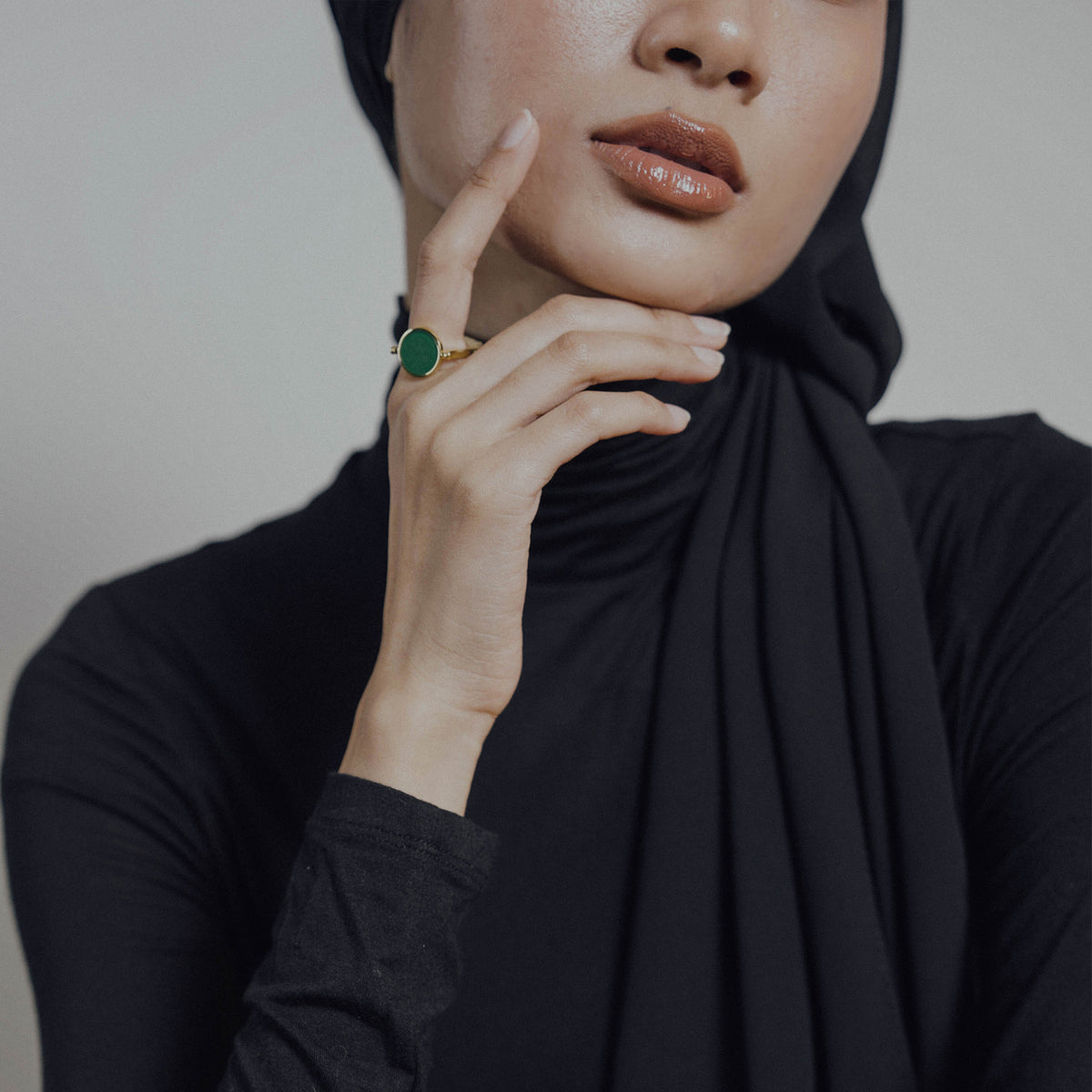 Woman wearing a black hijab with a close-up of her hand and ring.