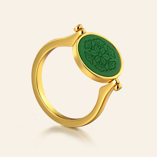 Gold ring with a green oval stone on a beige background