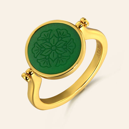 Gold ring with a green circular design on a beige background