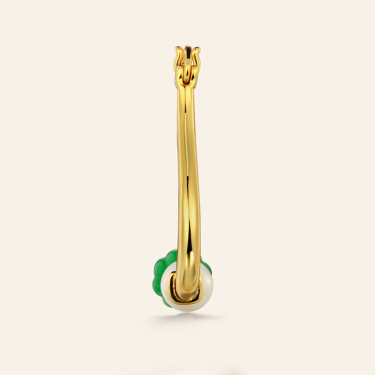 Gold hoop earring with green and pearl ball charm on a beige background