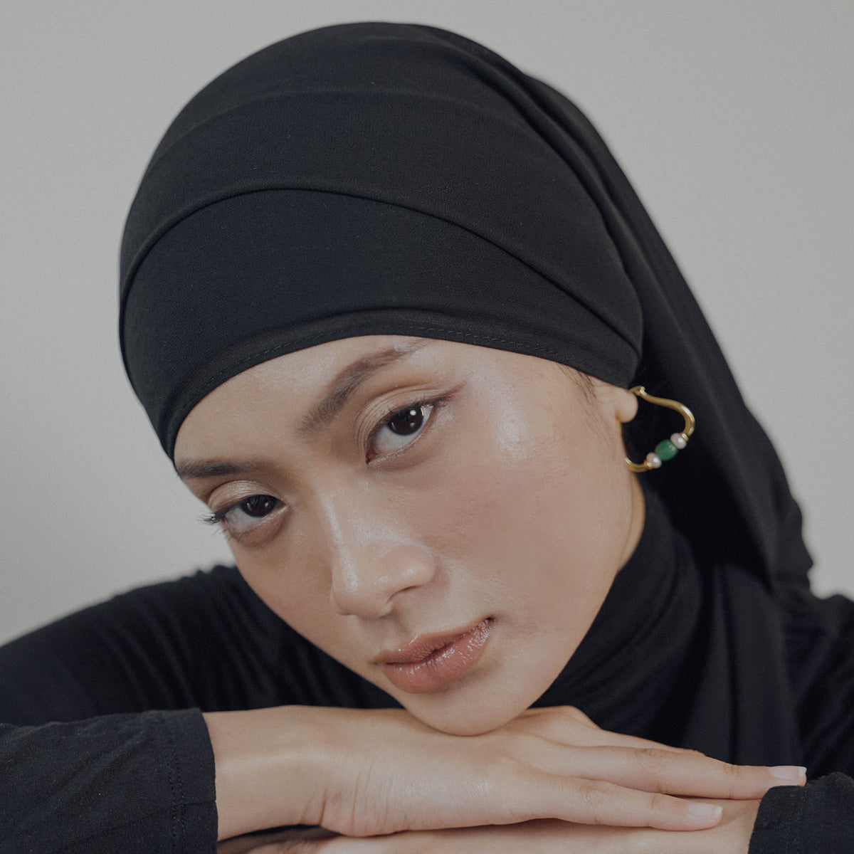 Woman wearing a black hijab with a neutral background