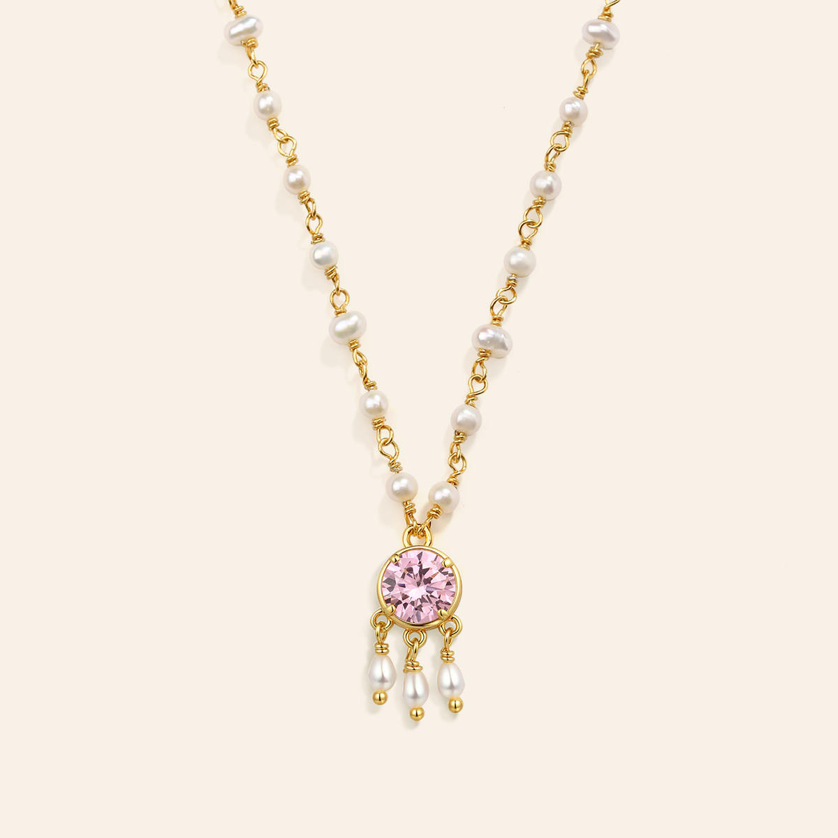 Necklace with pink gemstone and pearl drops on a beige background