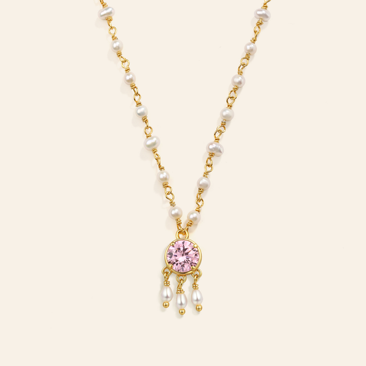 Necklace with pink gemstone and pearl drops on a beige background