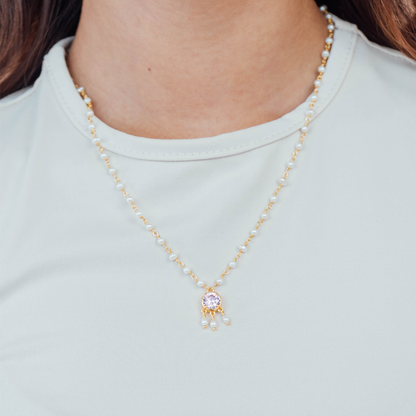 Necklace with a pendant worn by a person peatl and gold with pink gemstones